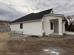 View of home's exterior featuring a shingled roof, brick siding, and a patio