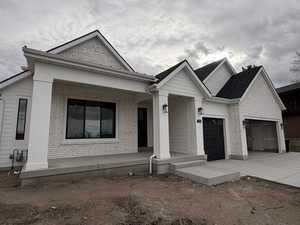View of front of house featuring brick siding, driveway, an attached garage, and a porch