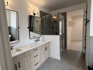 Bathroom with double vanity, a stall shower, and light tile patterned flooring