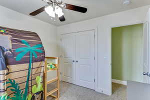 Bedroom with light carpet, ceiling fan, and a closet