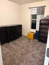 Bedroom with dark colored carpet and baseboards