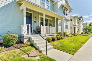 Doorway to property featuring covered porch, board and batten siding, a residential view, and a yard