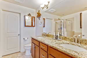 Full bathroom featuring a stall shower, double vanity, and light tile patterned flooring