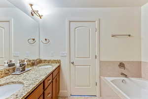 Bathroom with double vanity, a bath, and light tile patterned flooring