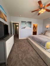 Bedroom featuring dark carpet, ceiling fan, and ensuite bath