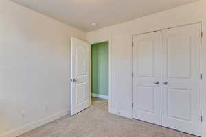 Unfurnished bedroom featuring light carpet and a closet