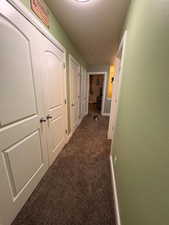 Hallway featuring dark carpet and baseboards