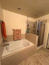 Full bath featuring a stall shower, a garden tub, and light tile patterned floors