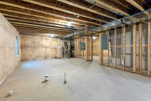 Below grade area with electric panel, strapped water heater, and heating unit