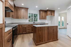 Kitchen with black range with electric cooktop, light wood-style floors, custom exhaust hood, light stone countertops, and recessed lighting