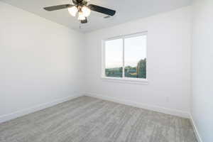 Carpeted spare room featuring baseboards and a ceiling fan