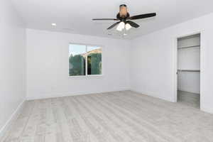 Unfurnished bedroom featuring a spacious closet, light carpet, a ceiling fan, and recessed lighting
