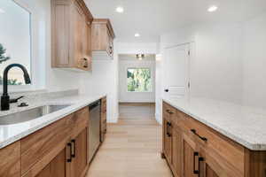 Kitchen featuring recessed lighting, brown cabinets, light wood finished floors, and light stone counters