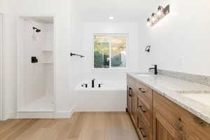 Bathroom with light wood-style flooring, double vanity, a garden tub, a shower stall, and recessed lighting