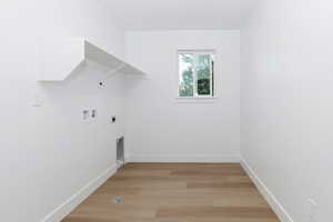 Laundry area with light wood finished floors, hookup for a washing machine, and electric dryer hookup