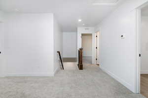 Empty room with light carpet and recessed lighting