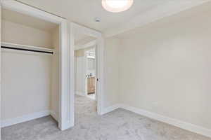 Unfurnished bedroom with light colored carpet and a closet