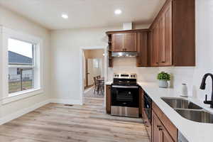 Kitchen featuring electric range, open shelves, light wood finished floors, recessed lighting, and light stone countertops