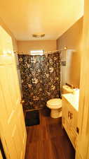Bathroom with vanity, a textured ceiling, dark wood-style flooring, and shower / bath combo with shower curtain