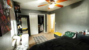 Bedroom with a closet, light colored carpet, and a ceiling fan