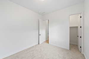 Unfurnished bedroom with a spacious closet and light colored carpet