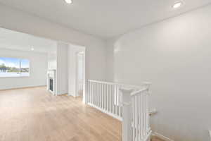 Hall featuring recessed lighting, light wood-type flooring, and an upstairs landing