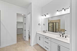 Full bathroom with a shower stall, a walk in closet, double vanity, light tile patterned flooring, and a tub