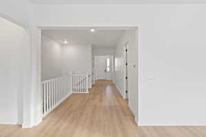 Corridor featuring an upstairs landing, light wood-style floors, and recessed lighting
