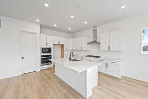 Kitchen with white cabinets, stainless steel appliances, a center island with sink, recessed lighting, and a kitchen bar