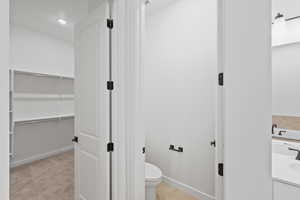 Full bath with vanity, a walk in closet, light tile patterned floors, light colored carpet, and recessed lighting