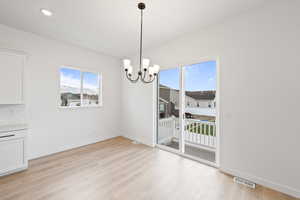 Unfurnished dining area with plenty of natural light, light wood finished floors, a chandelier, and recessed lighting