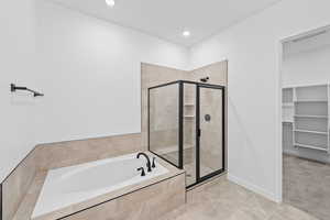 Full bathroom with a spacious closet, a bath, a stall shower, light tile patterned flooring, and recessed lighting