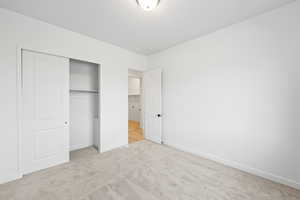 Unfurnished bedroom with light colored carpet and a closet