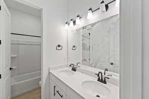 Bathroom featuring double vanity, light tile patterned flooring, and bath / shower combo with glass door