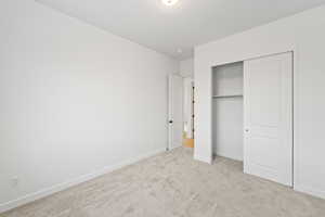 Unfurnished bedroom featuring light carpet and a closet