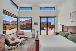 Bedroom featuring light wood-style floors, access to outside, and a high ceiling