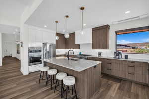 Kitchen featuring modern cabinets, decorative light fixtures, stainless steel appliances, backsplash, and dark wood-type flooring