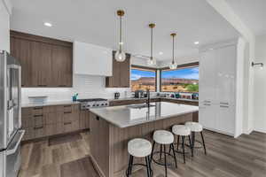 Kitchen featuring modern cabinets, hanging light fixtures, decorative backsplash, light wood-style floors, and recessed lighting