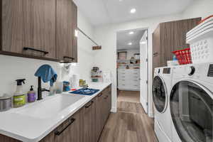Washroom with light wood finished floors, separate washer and dryer, recessed lighting, and cabinet space