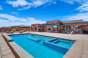 View of swimming pool with a patio area, a pool with connected hot tub, a fenced backyard, and an outdoor hangout area