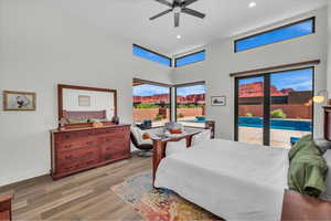 Bedroom with access to exterior, light wood-style flooring, a high ceiling, ceiling fan, and recessed lighting