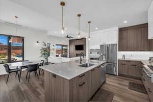 Kitchen with modern cabinets, open floor plan, ceiling fan, tasteful backsplash, and light stone countertops