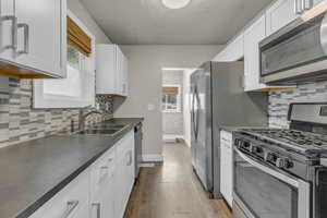 Kitchen featuring tasteful backsplash, stainless steel appliances, white cabinetry, and a textured ceiling