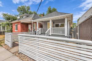 View of front of home featuring a fenced front yard, a shingled roof, a porch, and brick siding