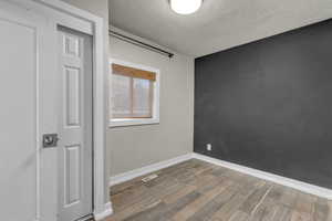 Empty room with a textured ceiling and light wood-style floors