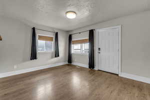 Unfurnished room with a textured ceiling and wood finished floors