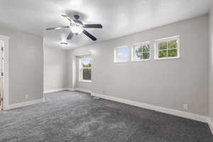 Empty room with a textured ceiling, carpet, and a ceiling fan
