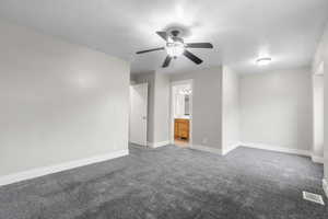 Unfurnished bedroom featuring carpet, ensuite bath, a textured ceiling, and a ceiling fan