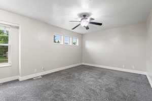 Carpeted empty room featuring a textured ceiling and ceiling fan