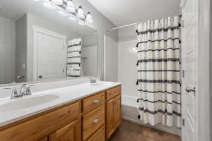 Full bathroom featuring shower / bathtub combination with curtain, double vanity, a textured ceiling, and dark tile patterned floors